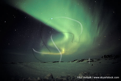 Swirling bands of Aurora Borealis over a snowy arctic landscape