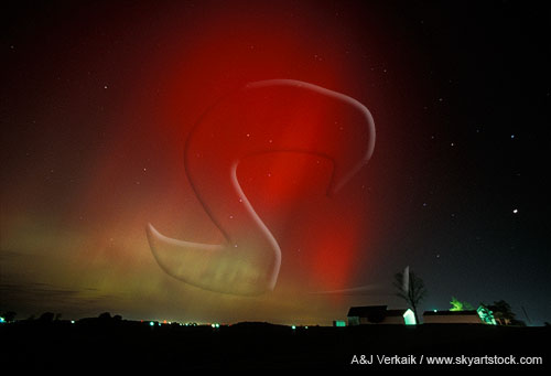 Red and green northern lights over a farm leave country folk in awe