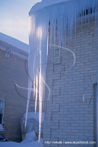 Very long icicles hang from the eaves of a house
