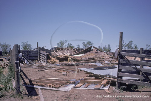 Broken building and fences in farmyard due to tornado damage