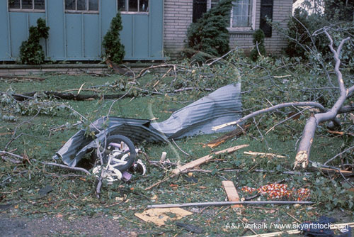 Twisted metal, branches and a tricycle damaged by a tornado
