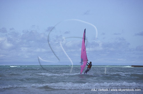 Man on board sail (windsurfer) enjoys wind and waves