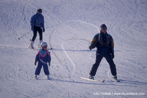 Parents and child skiing on snow-covered ski slope