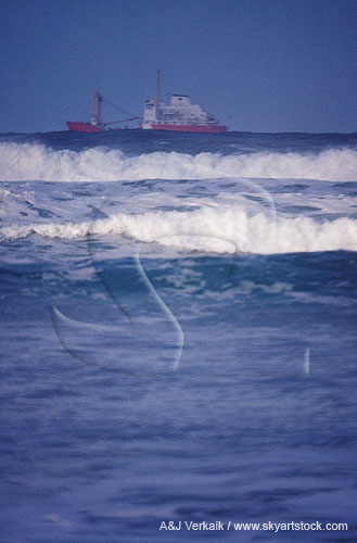 A ghostly ship plies the sea offshore as waves break
