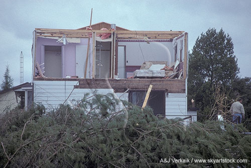 A tornado has ripped off the wall and roof of a house