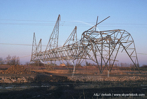 Mangled steel tower in a power corridor after a tornado strikes.
