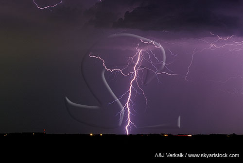 A single lightning bolt with fine filaments in a dusky sky