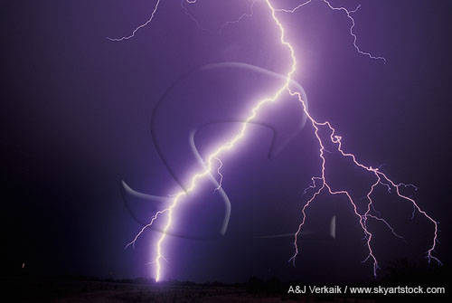 A very close highly electric lightning bolt sears the night sky