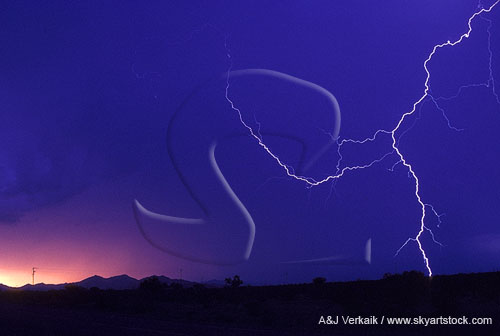 A single close lightning bolt against a red and blue sunset