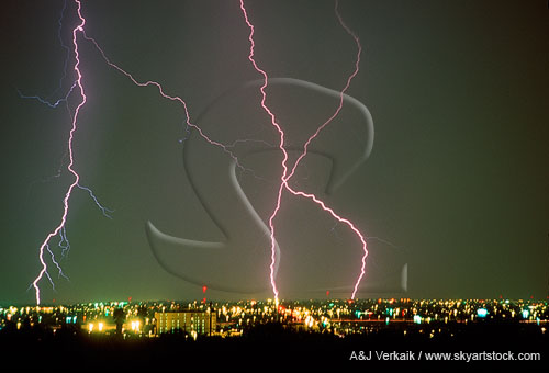 Close-up of cloud-to-ground lightning strikes over city buildings