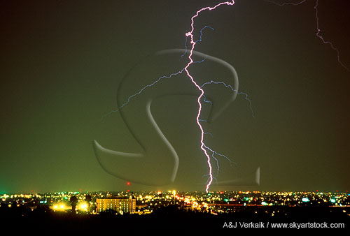 A single bolt of lightning strikes down into a city skyline at night