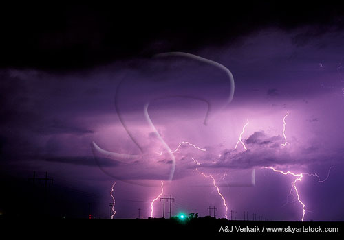 Distant cloud-to-ground lightning bolts cast a purple light