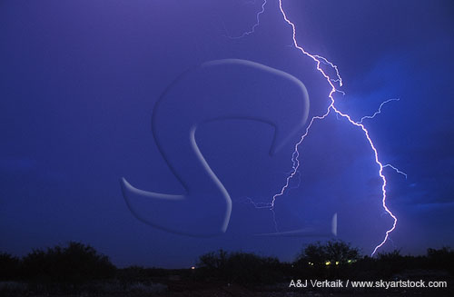 A single brilliant lightning bolt cuts through a deep blue dusk sky