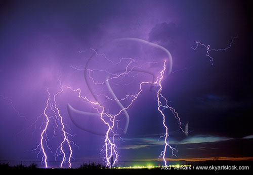 Bright cloud-to-ground lightning strikes in a sunset sky