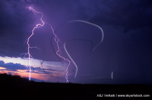 Cloud-to-ground lightning strikes drop down before a sunset sky