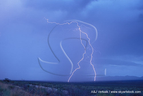 A forked lightning bolt strides across the desert in daylight