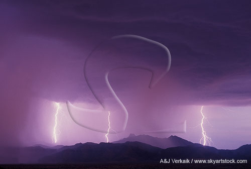 Lightning strikes in a dusky, pink sky over layered mountains