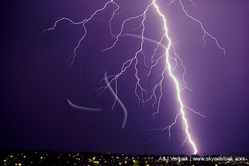 A close lightning bolt strikes over city lights
