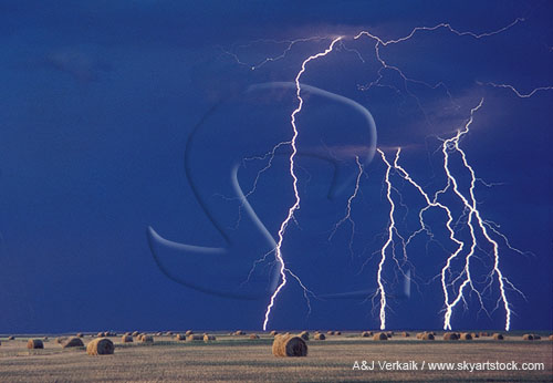 Brilliant close lightning bolts in daylight over bales of hay