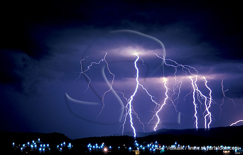 Brilliant cloud-to-ground lightning bolts over city lights
