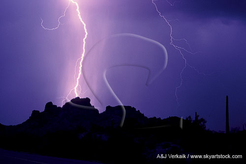 A single, bright lightning bolt hitting a mountain top peak
