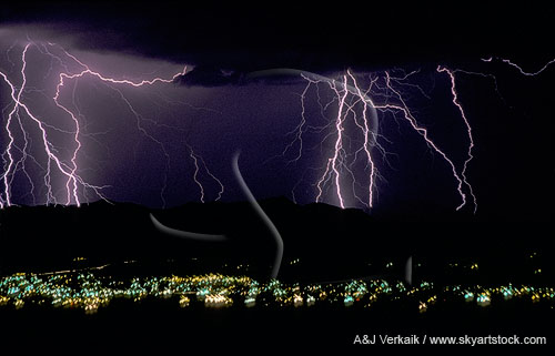 Lightning bolts strike behind a mountain above distant city lights