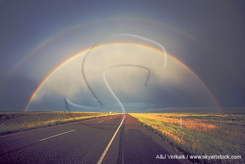 A full rainbow with secondary bow arches over a highway