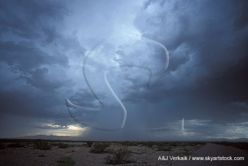 A stormy sky drops a gushing rain shower on a desert
