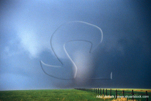 A large, wide tornado below a ruffled light wall cloud