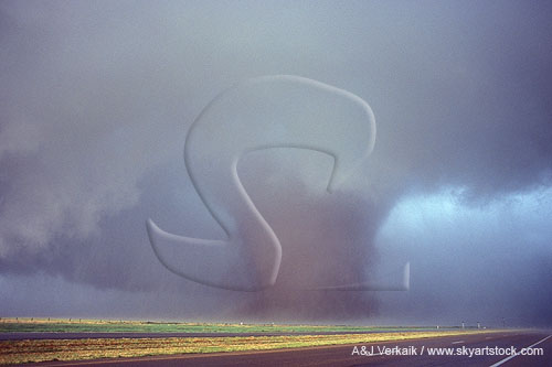A large wedge tornado stands like a thick tree trunk in the sky