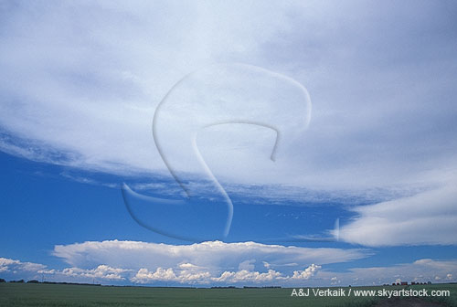 Smooth swathes of white cloud arch over a distant severe storm