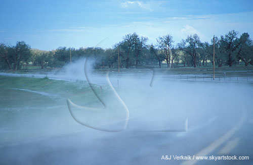 Steam fog lifts from the surface of a road after a hailstorm