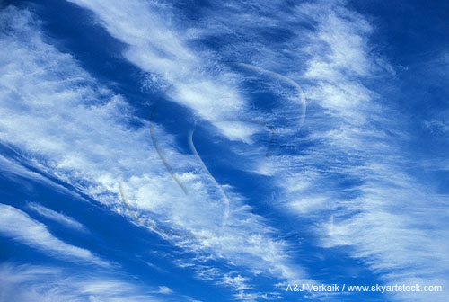 Silvery streaks of silken textured cloud stripe a deep blue abstract sky
