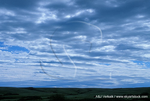 Cloud billows over rolling hills in a tranquil landscape