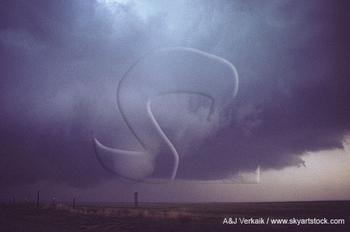 A large funnel cloud hangs from the wall cloud of a supercell storm
