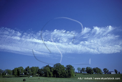 Cloud puffs and wisps in a band over fields