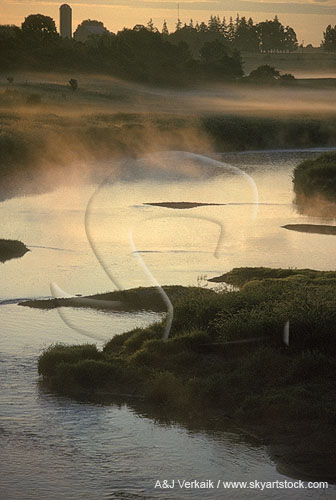 Fog hovers over a river in a mysterious sunrise landscape