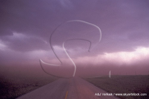 A cloud of blowing dust blocks visibility on a remote road