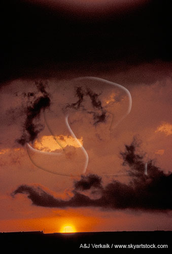 Sunset sky with ghostly clouds and the disk of the sun sinking