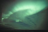 A swath of glowing green Aurora Borealis with clouds