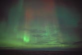 Green and red streaks of northern lights with clouds