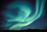 A blue-green phantom (Aurora Borealis) looms over arctic hills.