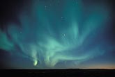 A swirling patch of blue-green northern lights in a starry sky