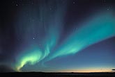 Blue and green swirls of northern lights in a starry twilight