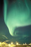 A ghostly fan of northern lights over an arctic settlement
