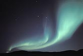 A sweeping band of northern lights over an arctic ridge