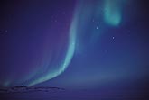 Streaky northern lights in a twilight sky with stars
