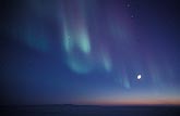Aurora Borealis in an arctic sky with a three-quarter moon