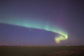 A swirling band of northern lights in a twilight prairie sky