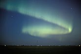 An S-shaped band of northern lights in a twilight prairie sky